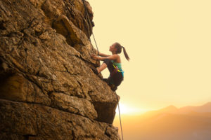 A woman climbing up a large rock